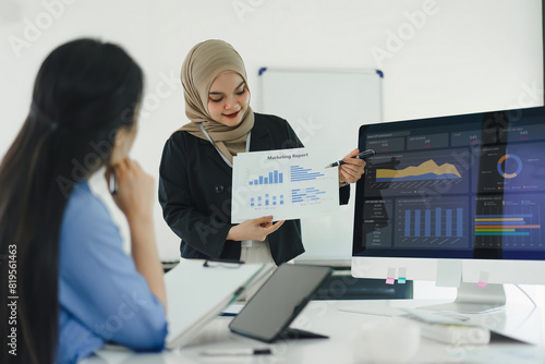 Two professional women discuss and analyze financial data and marketing strategies, presenting and brainstorming to increase company profits.