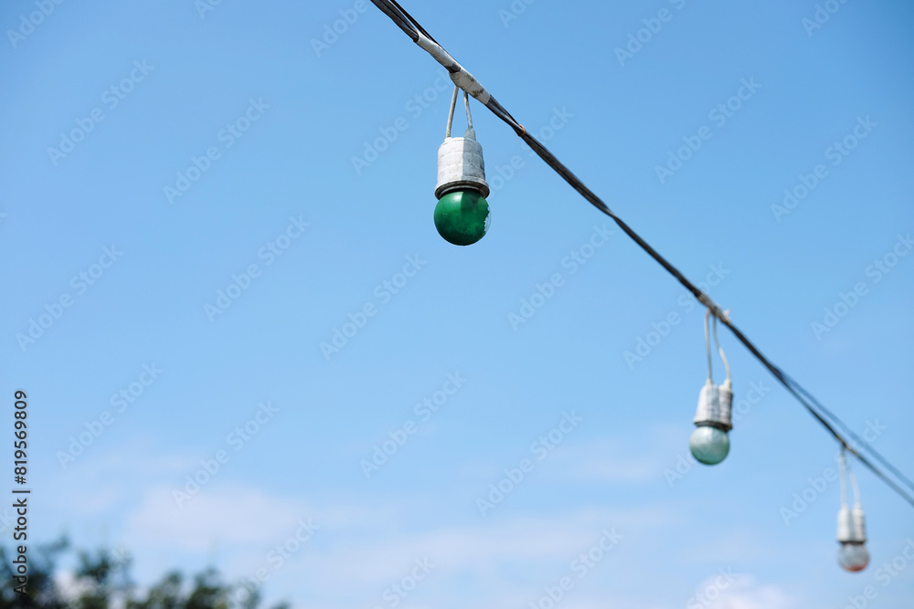 Equipped and electrical with light bulbs is hanging in the wind and sunlight on blue sky Equipped and electrical with light bulbs is hanging in the wind and sunlight on blue sky