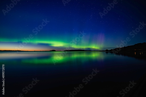 Northern light dancing over calm lake in Farnebofjarden national park in north of Sweden