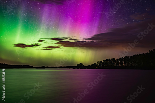 Northern lights dancing over calm lake in Farnebofjarden park in north of Sweden.
