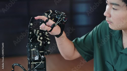 In a technical college an enthusiastic Asian teenage boy tests a robot hand and arm exploring technology for educational skill development. Embracing AI in futuristic learning.