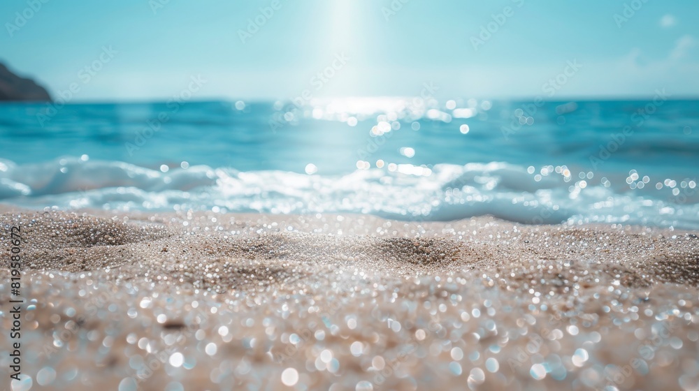 Close-up shot of sand with sun reflections on water, clear blue sky and distant cliffs visible Close-up shot of sand with sun reflections on water, clear blue sky and distant cliffs visible