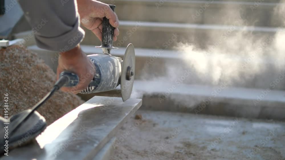 A man is using a grinder to cut a piece of concrete A man is using a grinder to cut a piece of concrete