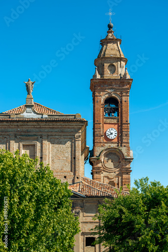 Church with belfry and clock under blue sky in Italy.