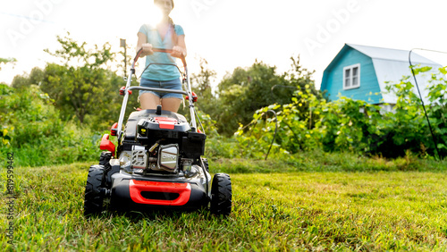 Obraz na plátně Girl with a lawn mower at her dacha
