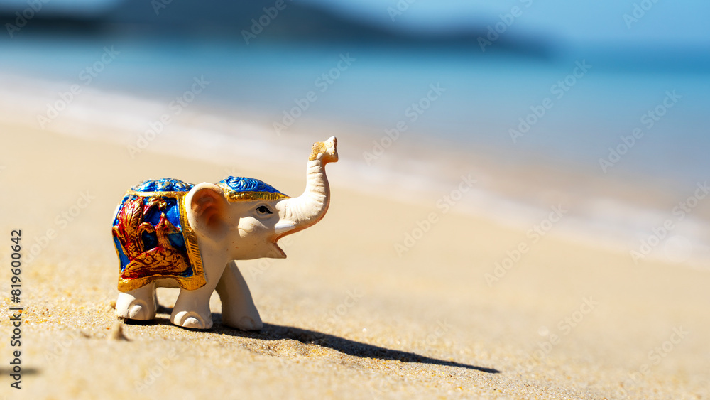 Obraz premium Elephant figurine on the beach sunbathing, vacation and travel concept