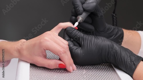 The master of the manicure saws and attaches a nail shape during the procedure of nail extensions in the beauty salon. Professional care for hands. photo