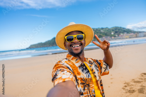 Obraz na plátne African american man taking selfie gesturing victory on beach