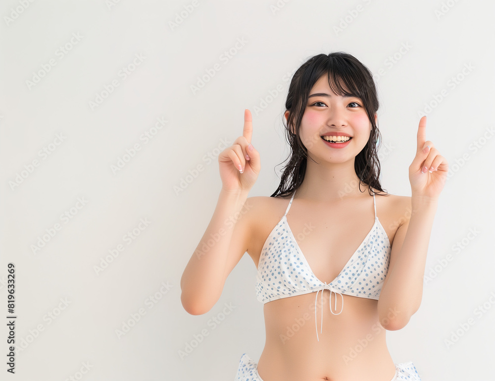 Happy Young Woman in White Bikini Pointing Upwards Against White Background Happy Young Woman in White Bikini Pointing Upwards Against White Background