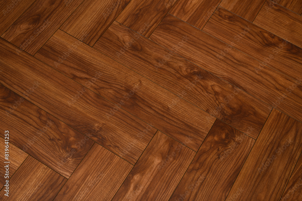 Naklejka premium Drewniany ciemnobrązowy parkiet na podłodze z bliska, przeplatany na ukos