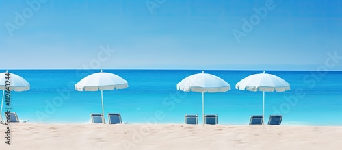 Tranquil beach scene with blue straw umbrellas overlooking a turquoise sea and clear blue skies perfect for a relaxing vacation or a copy space image © Ilgun