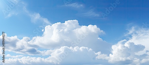 Fluffy white clouds floating in the clear blue sky providing a serene background for a copy space image