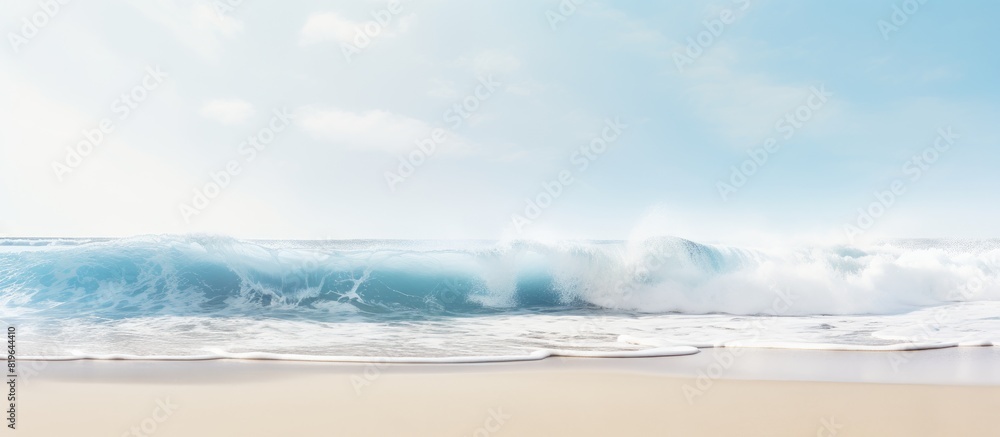 A white crested sea wave crashes onto a sandy beach in a wave background image with copy space