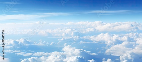 A captivating aerial perspective of fluffy clouds against a blue sky above the ocean seen from an airplane window with copy space image