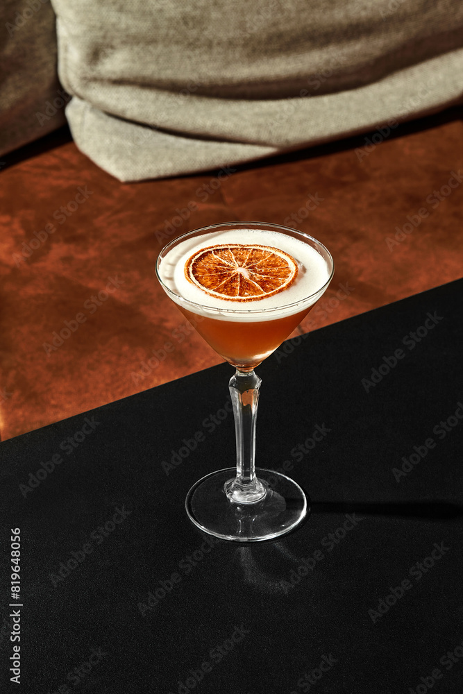 Glass of frothy almond sour cocktail with dried grapefruit slice