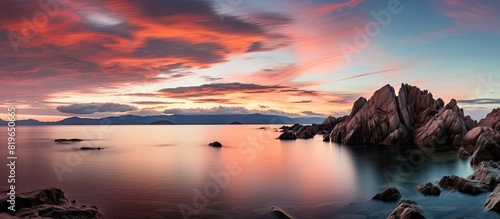 A serene coastal sunset scene with rocks in the water a stunning cloudscape and a peaceful ambiance evoking relaxation and meditation ideal for a copy space image
