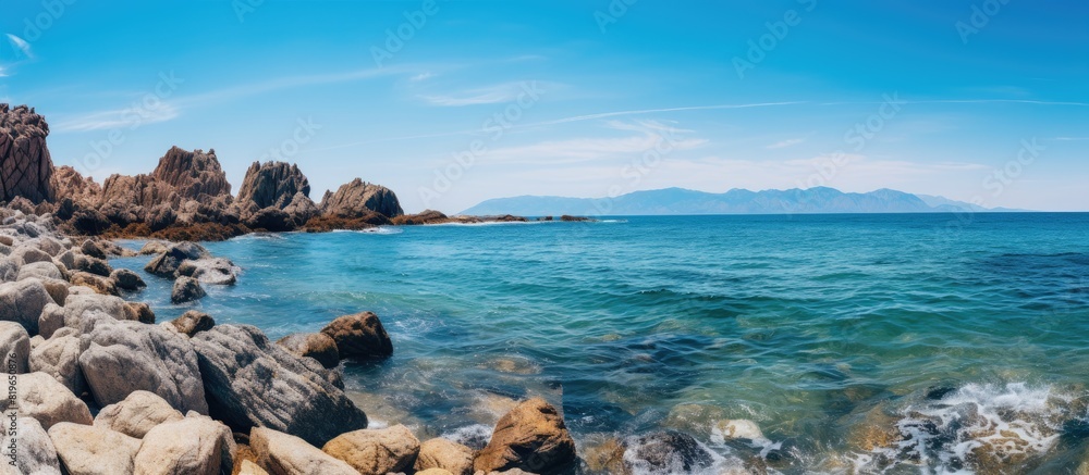 Scenic view of rocks by the sea under a clear blue sky with copy space image
