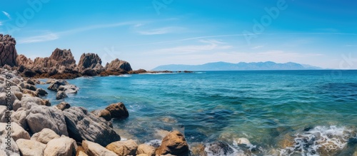 Scenic view of rocks by the sea under a clear blue sky with copy space image