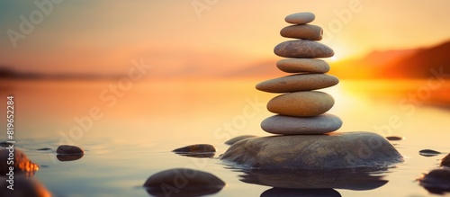Achieve Zen and peace by balancing a stone on a stack of rocks against a sunset background in the evening creating a calming atmosphere with copy space image