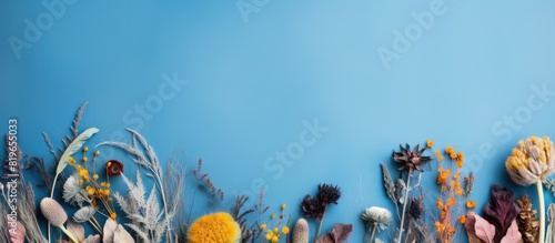 Top view of a border frame made of dried flowers and leaves on a blue background with copy space image