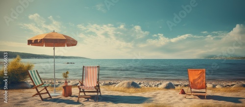 An image with beachfront chairs a trampoline and a beautiful seaside view perfect for sitting sunbathing against the backdrop of changing seasons by the sea. Copy space image