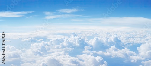 Fototapeta Naklejka Na Ścianę i Meble -  A captivating aerial perspective of fluffy clouds against a blue sky above the ocean seen from an airplane window with copy space image
