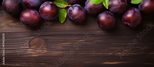 Top view of ripe juicy plums on a wooden surface with copy space image