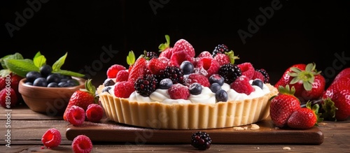 Delicious fruit and berry tart dessert with sprinkled sugar on a wooden surface The cake is adorned with raspberries figs strawberries cherries and cream set against a copy space image