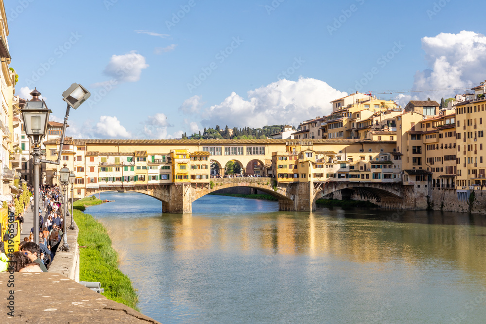 Obraz premium Florence, Italy - April 10, 2024: View of the Vecchio Bridge in Florence with tourists crowding its surroundings in Florence, Italy