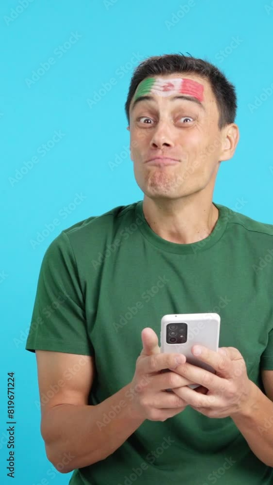 Mexican supporter looking at his mobile smiling and showing it. Mexican supporter looking at his mobile smiling and showing it.
