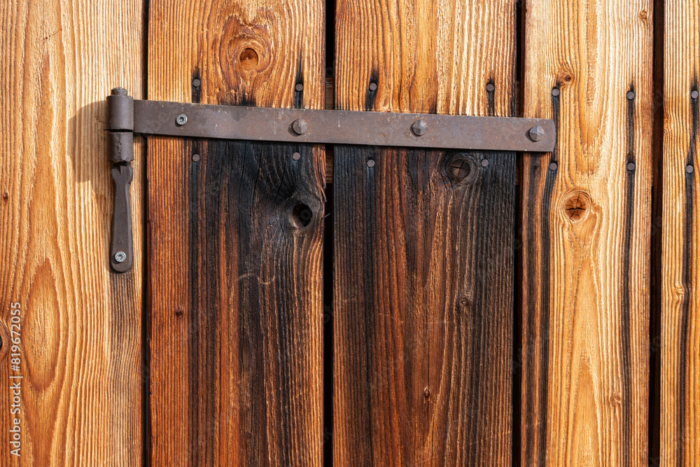 Closeup brown wooden door texture with rusty iron hinge Closeup brown wooden door texture with rusty iron hinge