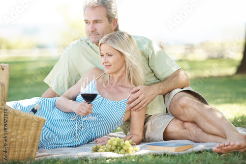 Happy, couple and relax with red wine on picnic for romance, holiday and adventure together. Woman, man and smile with love at countryside on blanket for marriage, support or anniversary in Australia © peopleimages.com