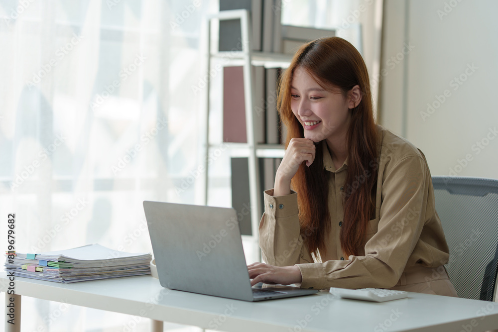 Asian businesswoman sits and works with laptop in contacting customers online. View details and discuss financial business information. Happiness in wealth Success in the office. Asian businesswoman sits and works with laptop in contacting customers online. View details and discuss financial business information. Happiness in wealth Success in the office.