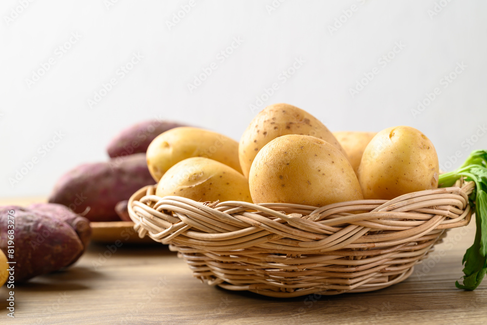 Raw potatoes and purple sweet potatoes on wooden table with white background, Food ingredient Raw potatoes and purple sweet potatoes on wooden table with white background, Food ingredient