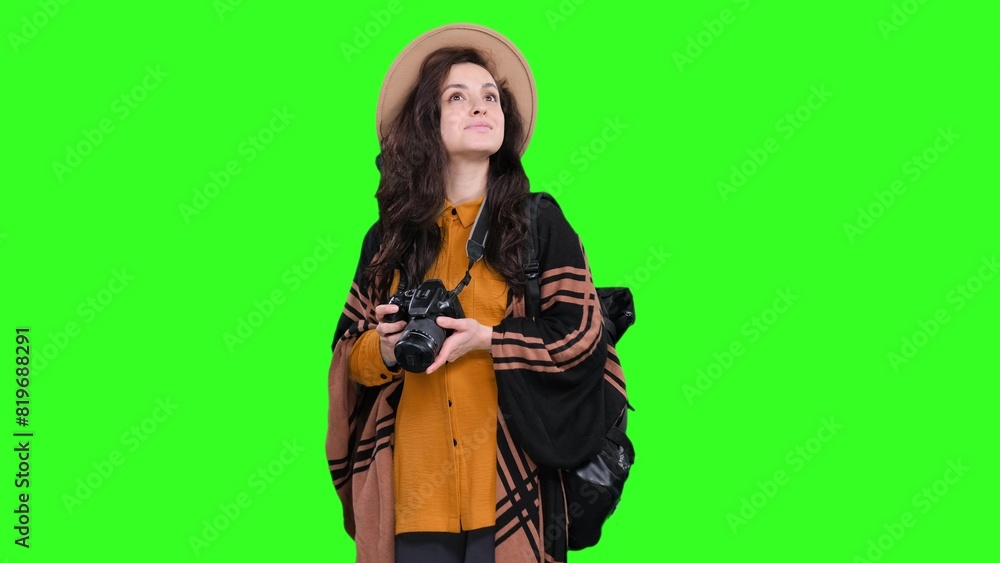 Smiling woman posing with camera and backpack on the chroma key