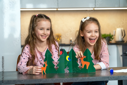 Happy girls funny make craft from colored paper and laugh. Children cut and glue animals in summer forest. Leisure, diy, handmade. Education