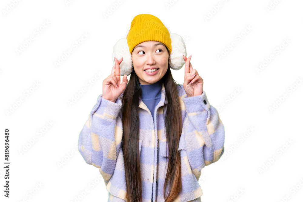 Young Asian woman wearing winter muffs over isolated chroma key background with fingers crossing Young Asian woman wearing winter muffs over isolated chroma key background with fingers crossing