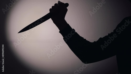 Hand holding knife and stabbing against red background photo