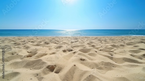 A sandy beach with clear blue skies and ample space in the sky for adding text or graphics promoting summer vacation destinations or activities