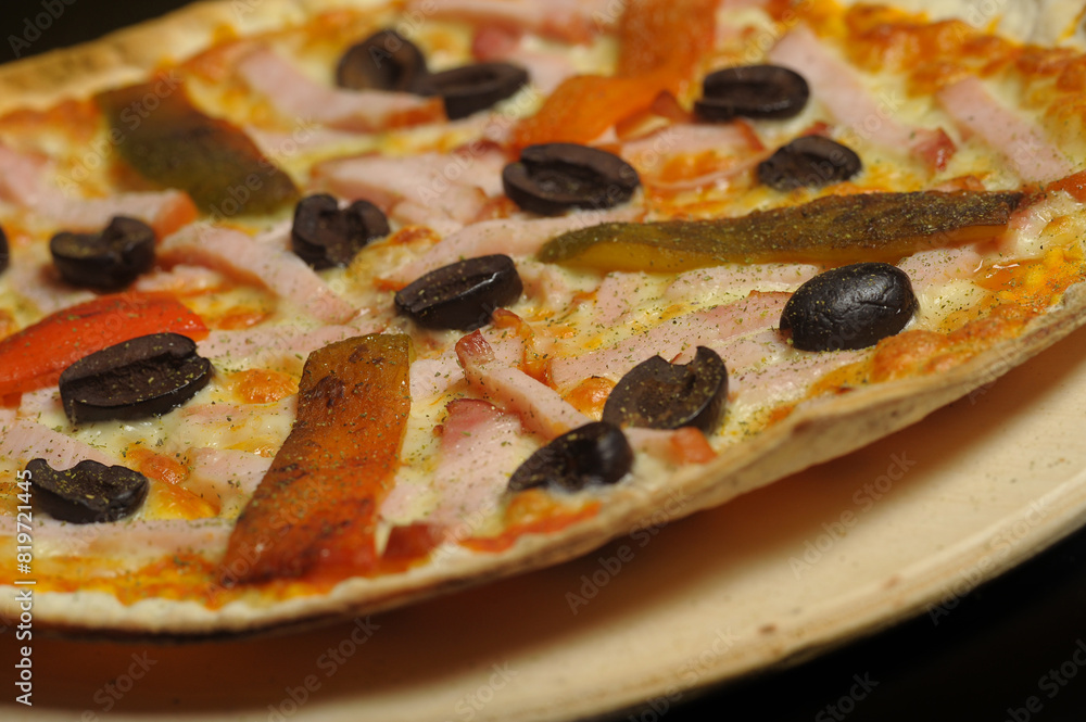 Pizza with ham, tomato and olives on a black background Pizza with ham, tomato and olives on a black background