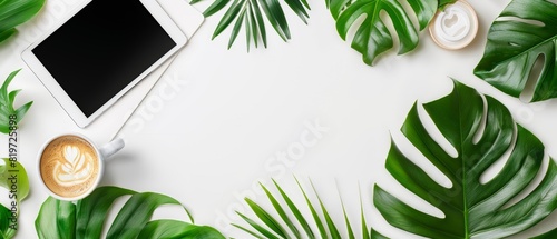 Flat lay of notepad, coffee, tablet, and green leaves on a white background