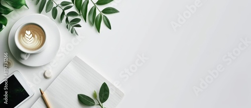 Top view of a clean workspace with a notepad  coffee cup  tablet  and green leaves on a white background  ideal for business visuals