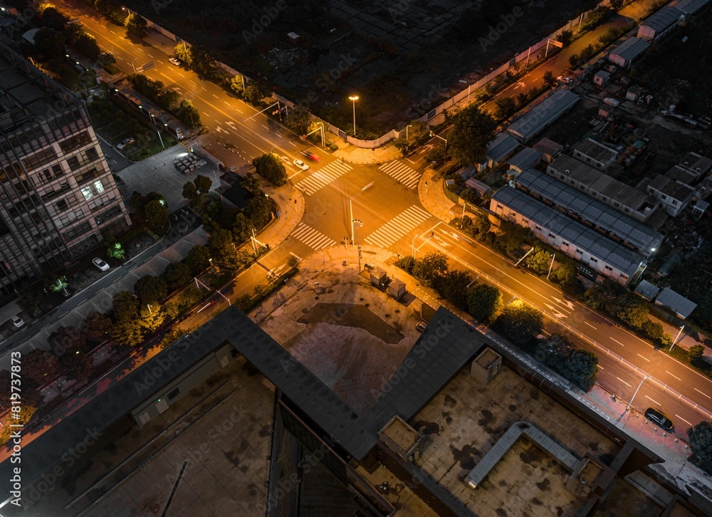 Aerial view of an intersection illuminated by orange-yellow street lights at night. Aerial view of an intersection illuminated by orange-yellow street lights at night.