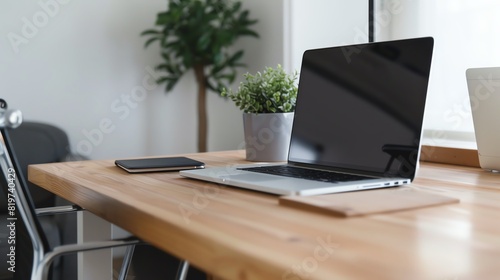 Modern office workspace with a laptop, tablet, and plant on a wooden desk. Bright, minimalistic setup highlighting productivity and organization.