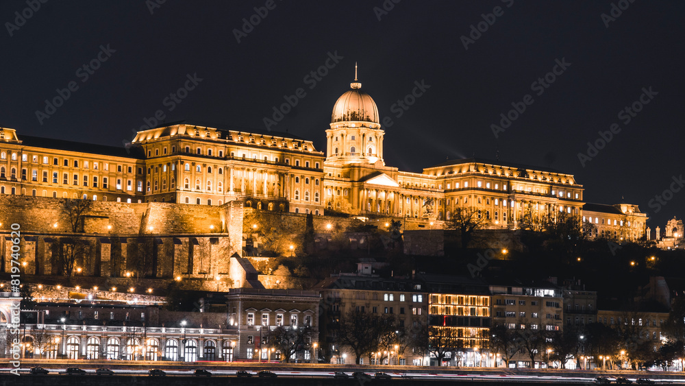 Obraz premium the view of a castle lit up at night as seen from across a river