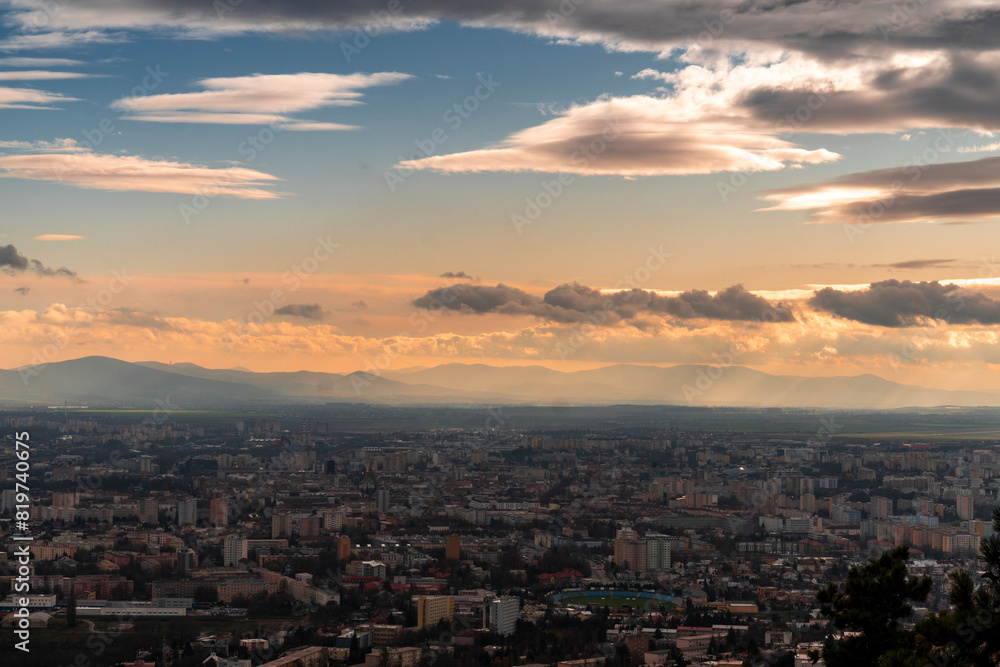 a city below the cloudy sky in the middle of sunset a city below the cloudy sky in the middle of sunset