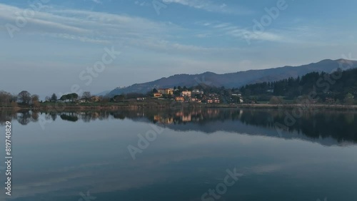 Drone of the reflection of houses in green field on the Lake Montorfano, with mountain behind them photo