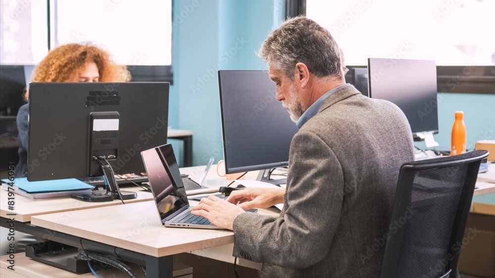 Manager using laptop at desk in coworking workspace Manager using laptop at desk in coworking workspace