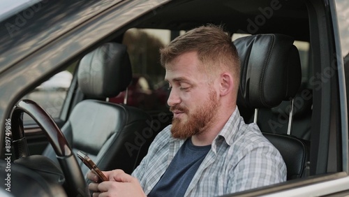 Male driver typing on the smartphone in the car. Slow motion © Nataliya