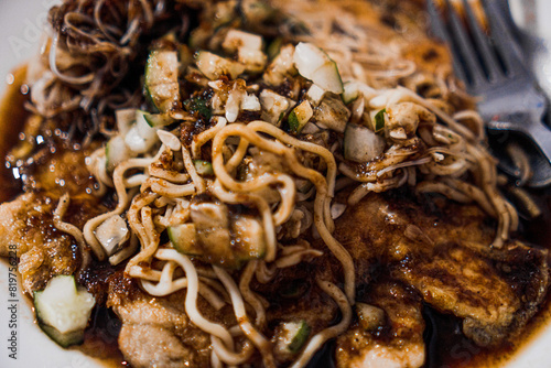 A super close-up photo of a dish of pempek lenggang, showcasing the details of the noodles, small cucumber slices topping, and the drizzle of pempek vinegar sauce photo